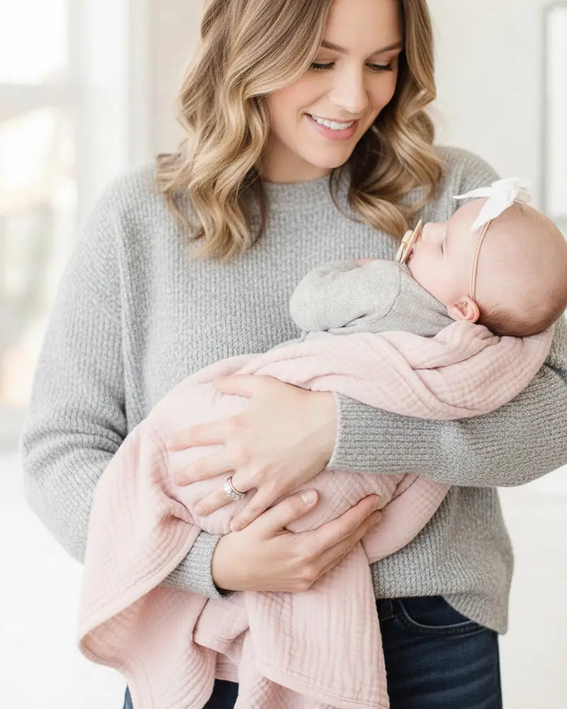Woman holding a baby wrapped in a pink saddle