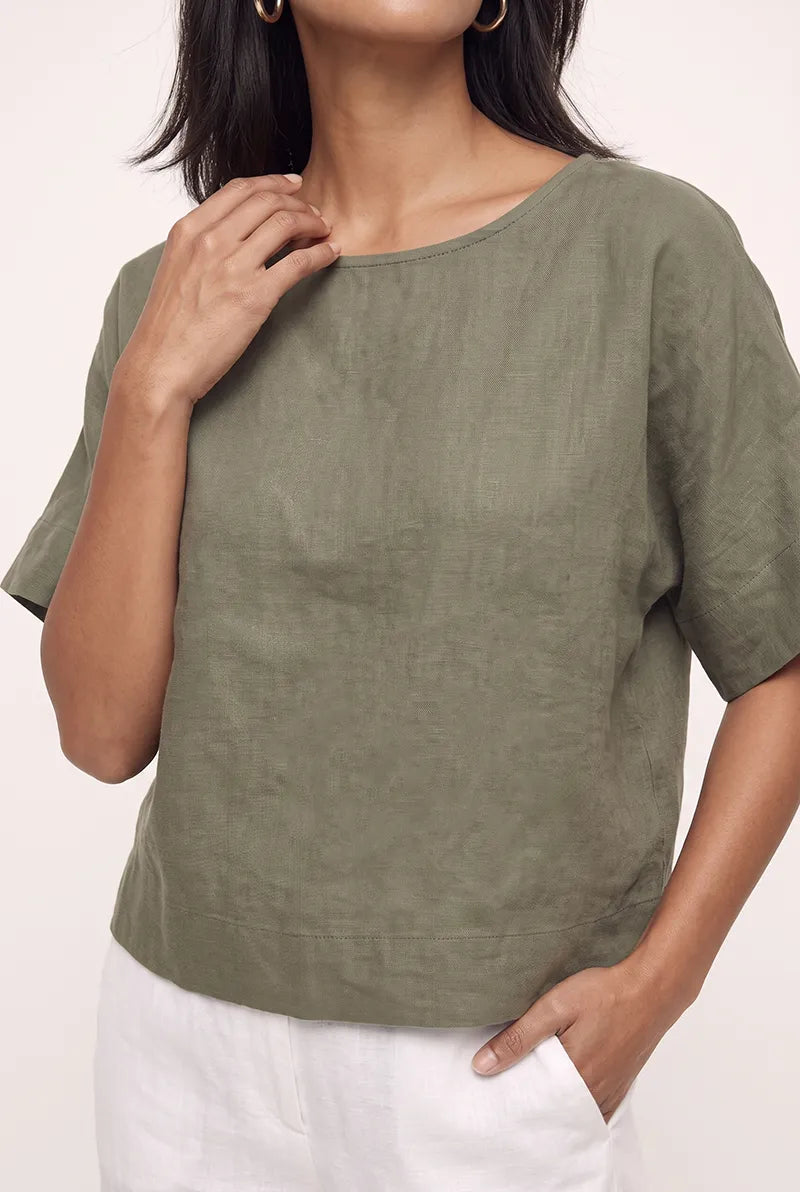Close-up of the olive green linen blouse top showing the natural linen texture and short sleeves