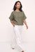 A woman modeling a short-sleeve olive green top and white wide-leg pants with gold-tone side buttons, standing against a plain off-white studio background.