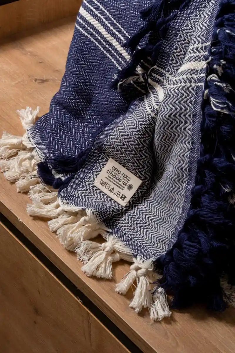 Blue and white patterned towel with tassels on a wooden surface