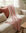 Pink muslin throw blanket on a beige sofa with cushions in a cozy living room.