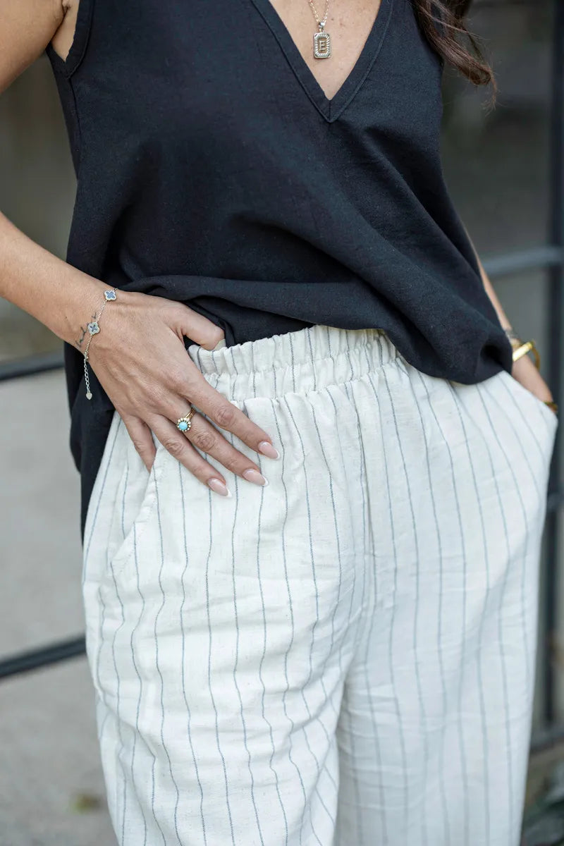 Person wearing a black top and white pinstriped pants with a blurred background