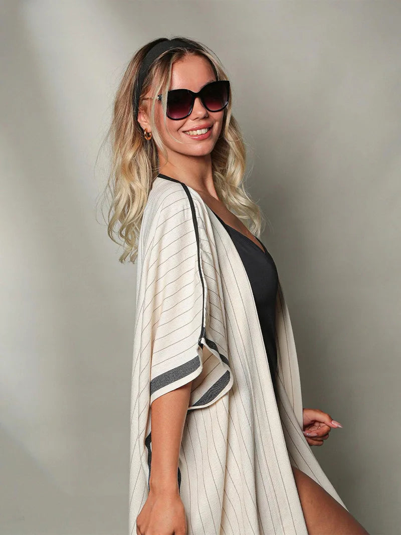 Woman wearing a swimsuit cover-up and sunglasses against a neutral background