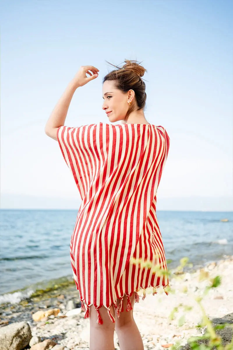Woman wearing a red and white striped beach cover upon a beach