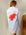 White shirt with red coral design on the back, worn by a person against a plain background