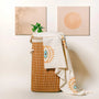 Retro evil eye beach towel on a wicker basket — Turkish cotton peshtemal with orange sun and evil eye pattern