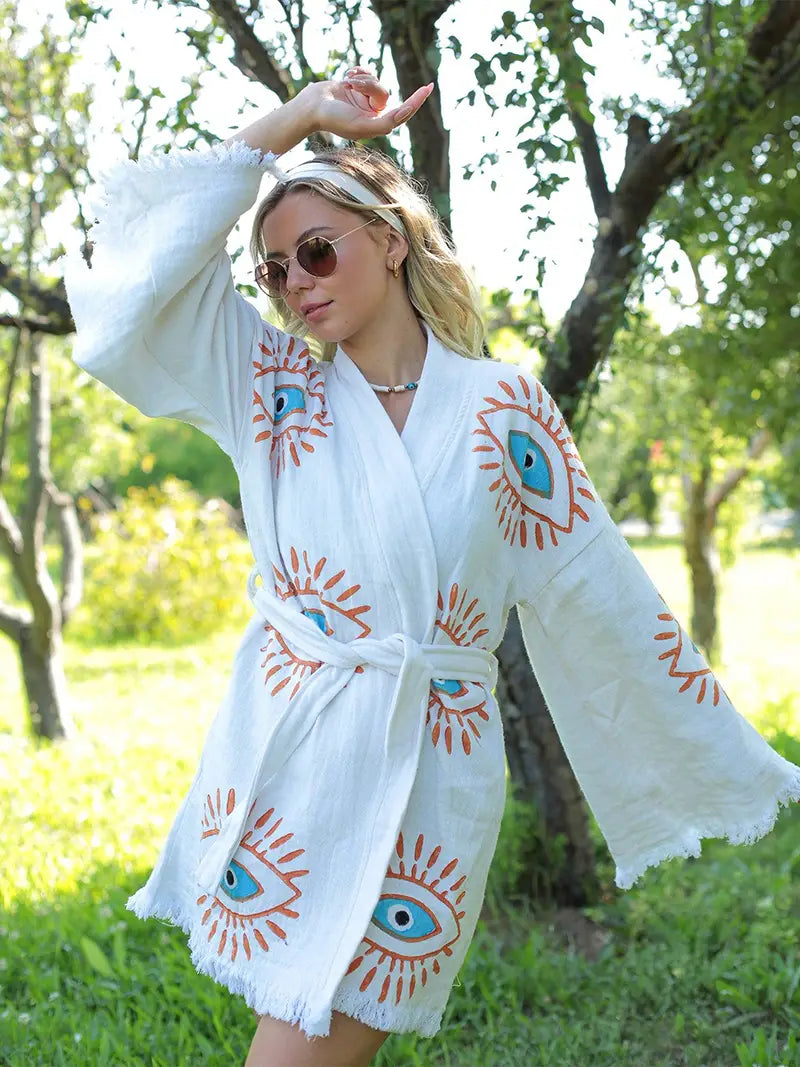 Woman wearing a white robe with eye designs outdoors