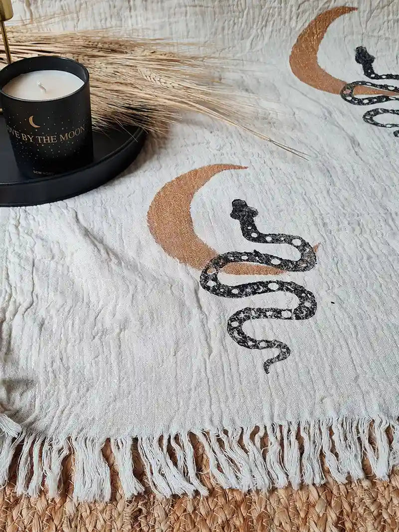 Turkish cotton blanket with snake and crescent moon design and candle on a textured surface