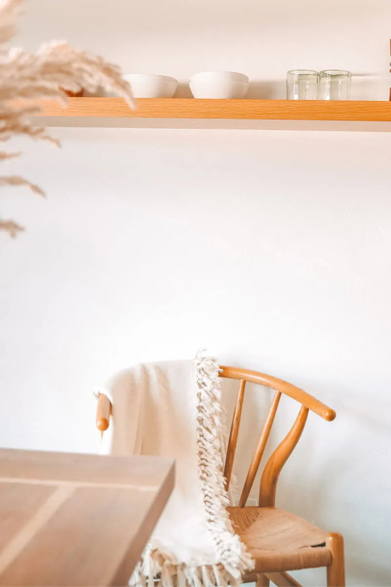 Wooden chair with a cream blanket draped over it.