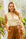 Woman in a beige sleeveless linen vest top and brown pants in a greenhouse — European Flax® linen