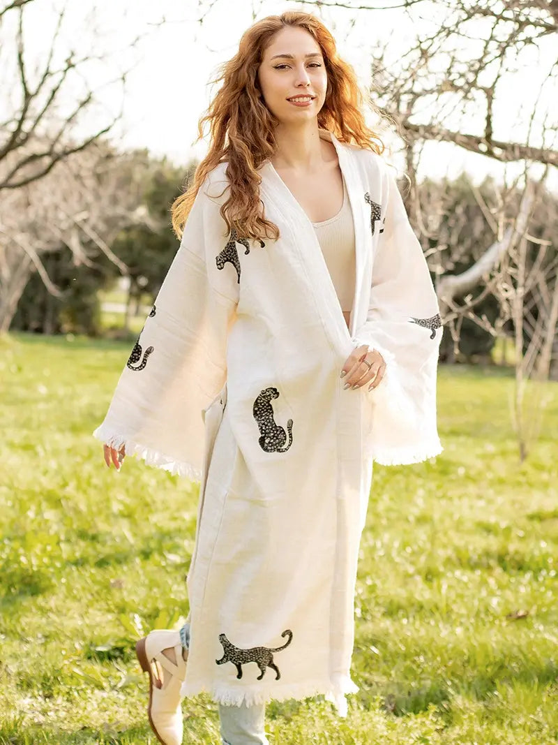 Woman wearing a white kimono with black cat designs in a park