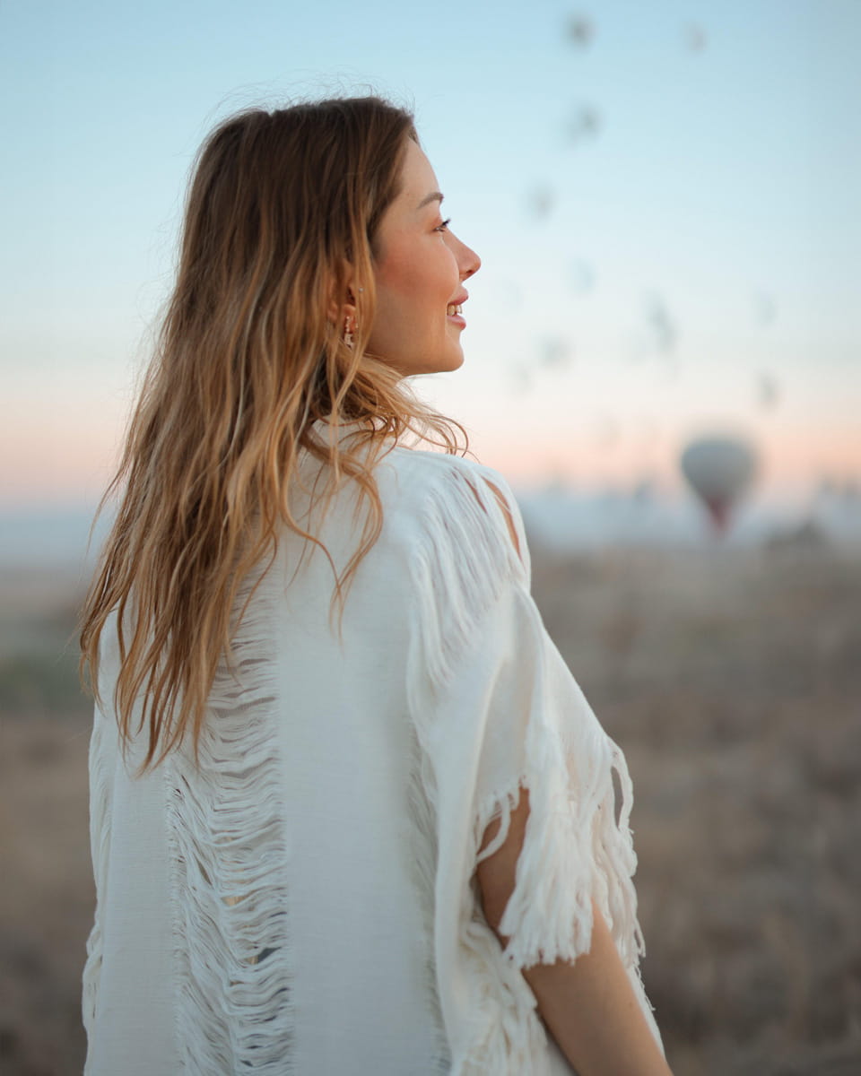 Woman wearing a fringe garment beach kimono cover up in a desert setting with a blurred background