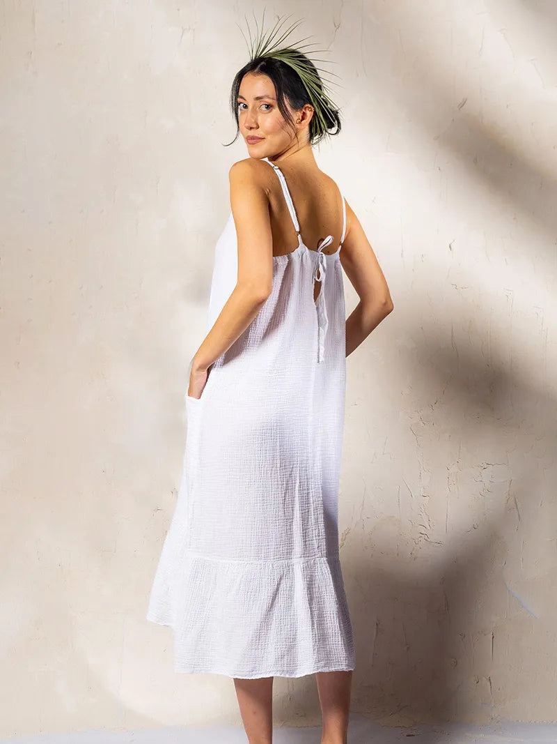 Woman wearing a white midi dress against a plain background