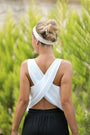 Woman in a white linen cross back top with crossed straps and black pants outdoors — natural linen
