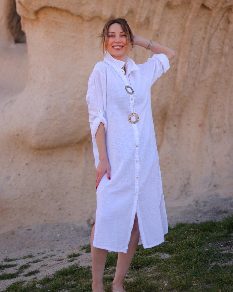 A woman grinning at the camera in a white midi dress