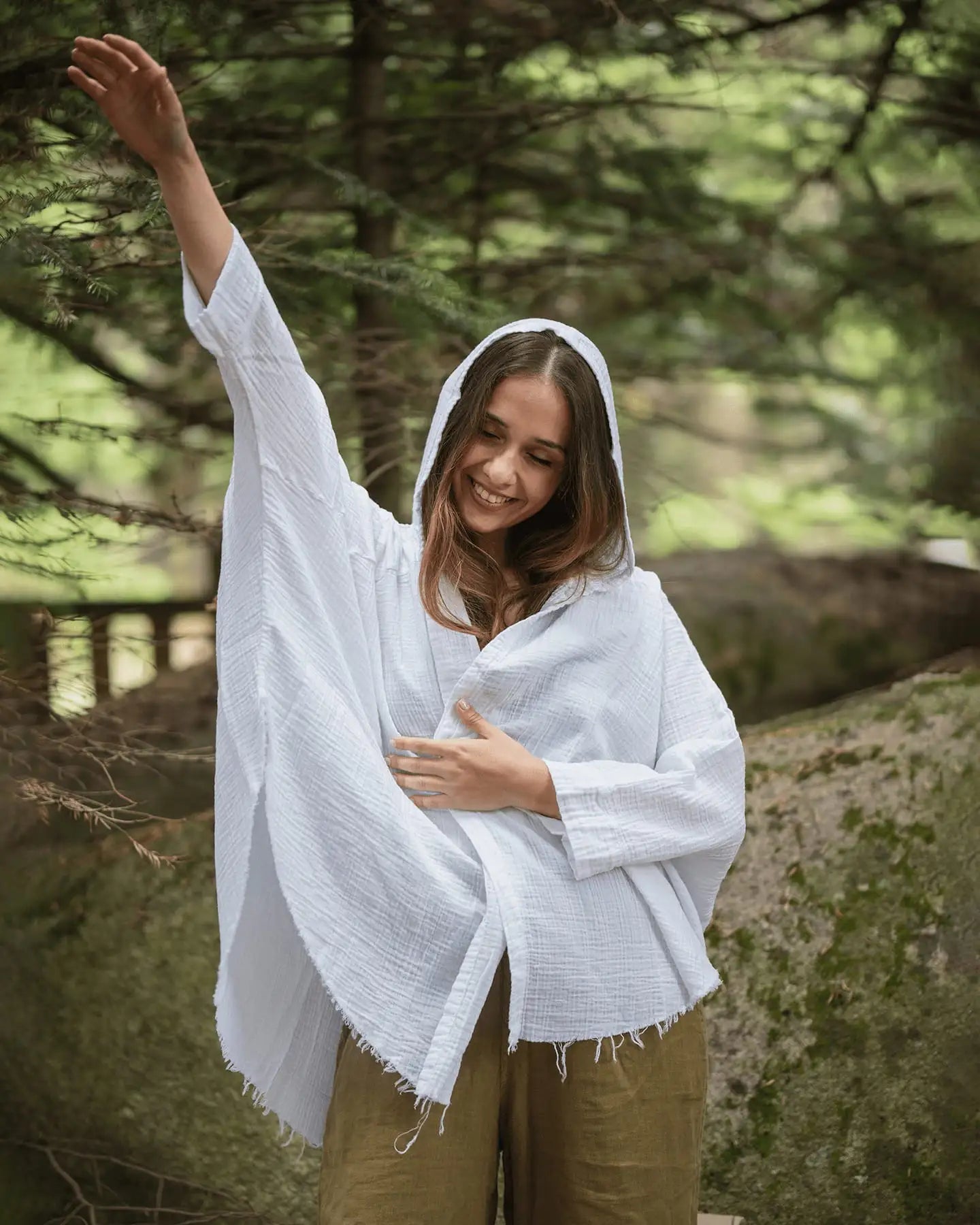 Woman wearing a white hooded cardigan in a forest setting