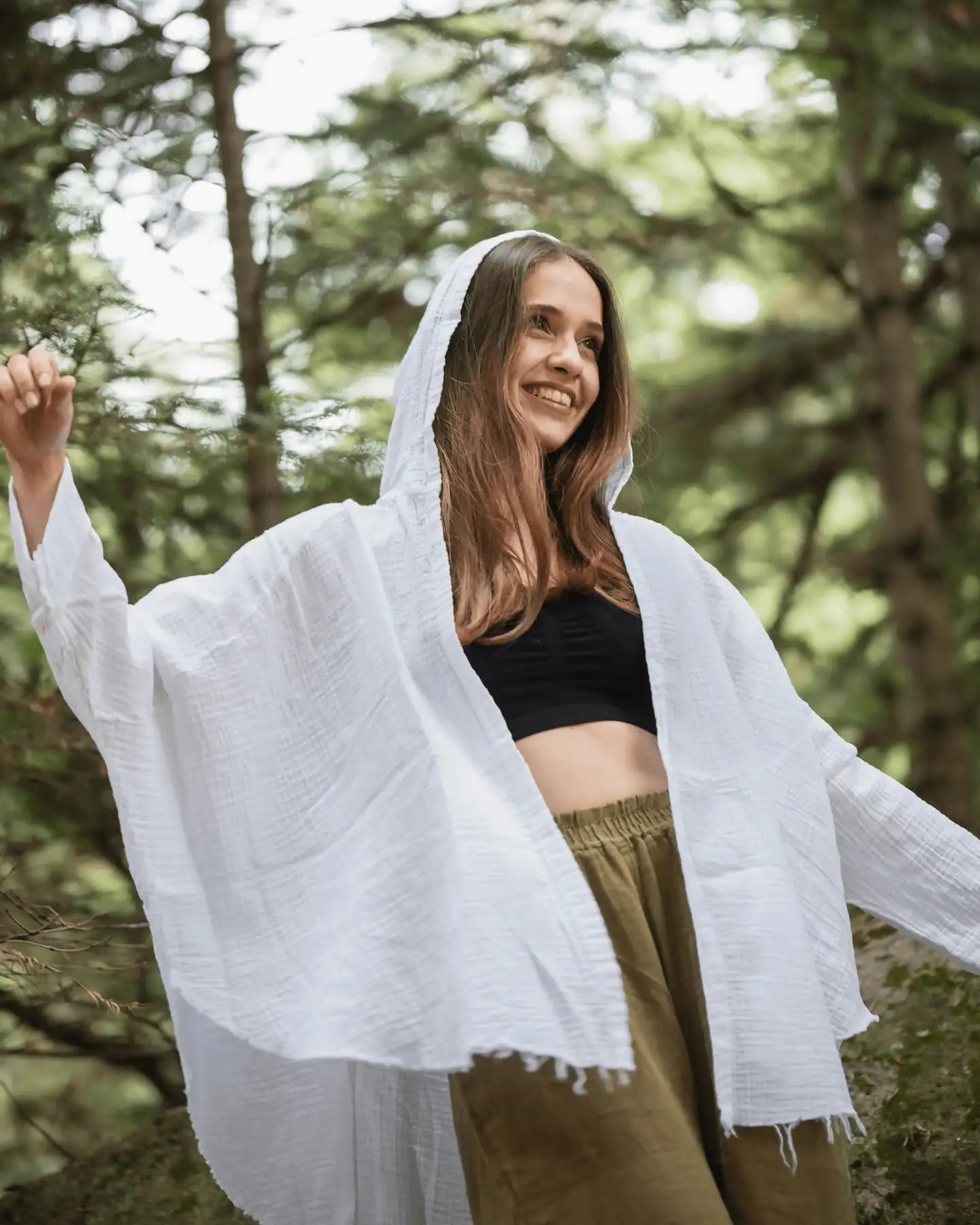 Woman wearing a white crinkle cotton hooded robe in a forest setting