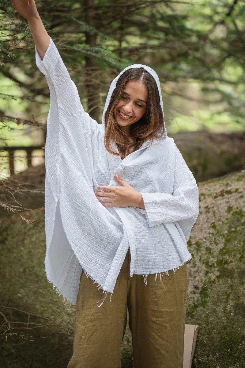Woman wearing a white hooded garment in a forest setting