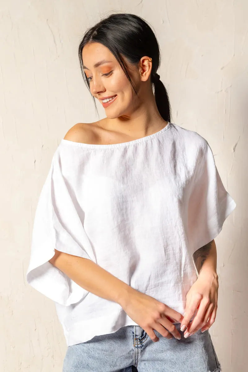 Woman wearing a white linen top against a plain background